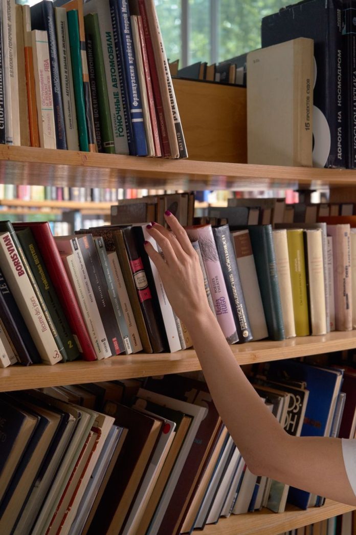 pexels-photo-8567079 a person looking for a book on a shelf